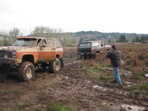 1978 Ford Bronco - Two 1978 Ford Broncos are stuck in a muddy field, with one vehicle being towed by the other.