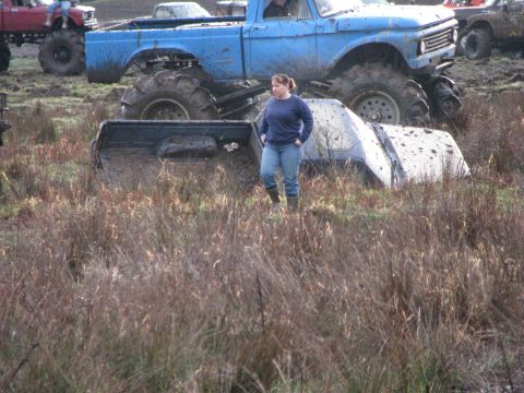1978 Ford Bronco - Mud bogging event with multiple lifted trucks in a muddy field.