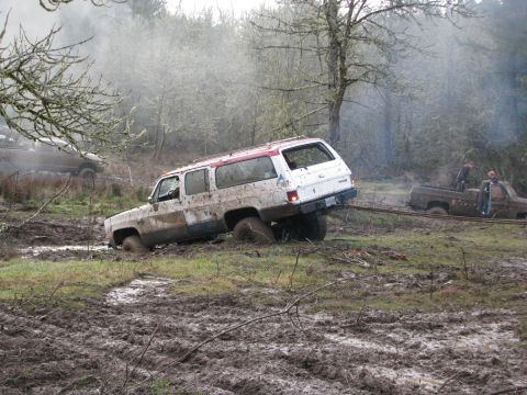 1978 Ford Bronco - Two vehicles are stuck in the mud, with one being towed out by the other.