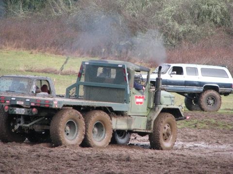 1978 Ford Bronco - A military truck tows a vehicle through muddy terrain, while another lifted SUV is visible.