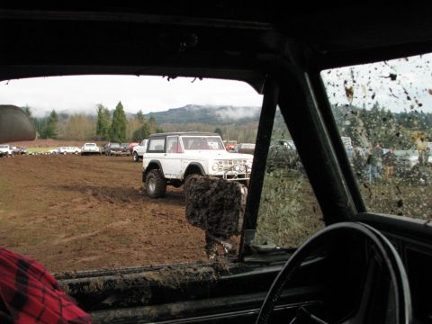 1978 Ford Bronco - A white 1978 Ford Bronco navigates a muddy off-road course, with other vehicles visible in the background.