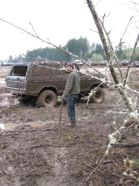 1978 Ford Bronco - A 1978 Ford Bronco is heavily covered in mud and appears to be stuck, with a person nearby holding a tow rope.