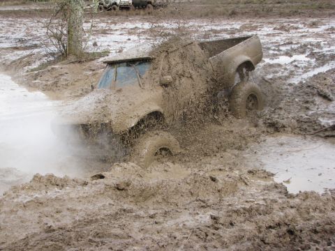 1978 Ford Bronco - Off-road vehicle struggling through deep mud, with another vehicle in the distance.