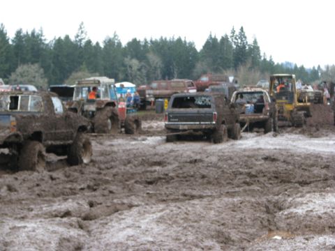 1978 Ford Bronco - Multiple off-road vehicles are stuck in deep mud during an event.