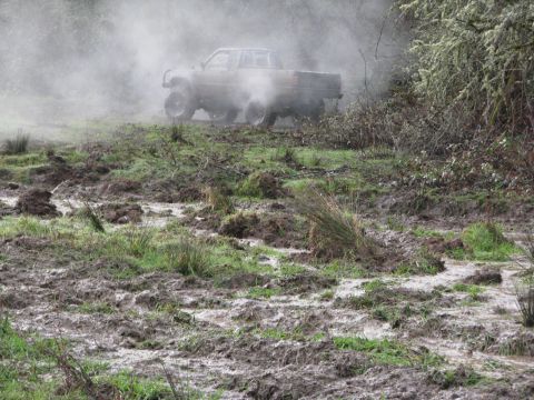 1978 Ford Bronco - A pickup truck navigates a challenging muddy terrain, kicking up smoke.