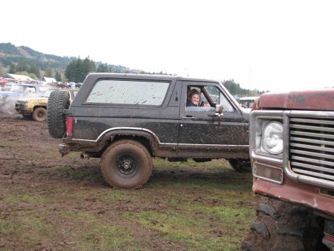 1978 Ford Bronco - 1978 Ford Bronco driving through mud with a smiling driver.
