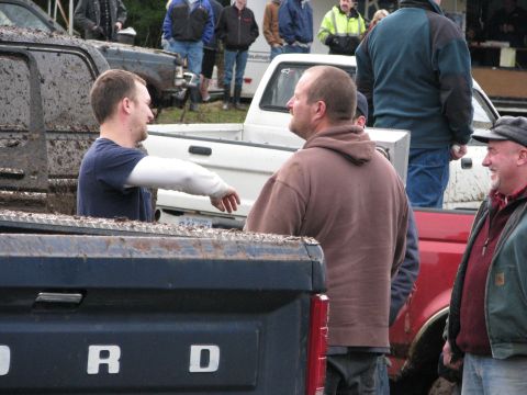 1978 Ford Bronco - Several pickup trucks are parked in a muddy area with people gathered around.