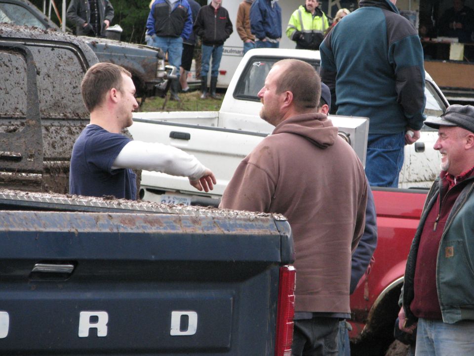 Muddy pickup trucks with people standing around them
