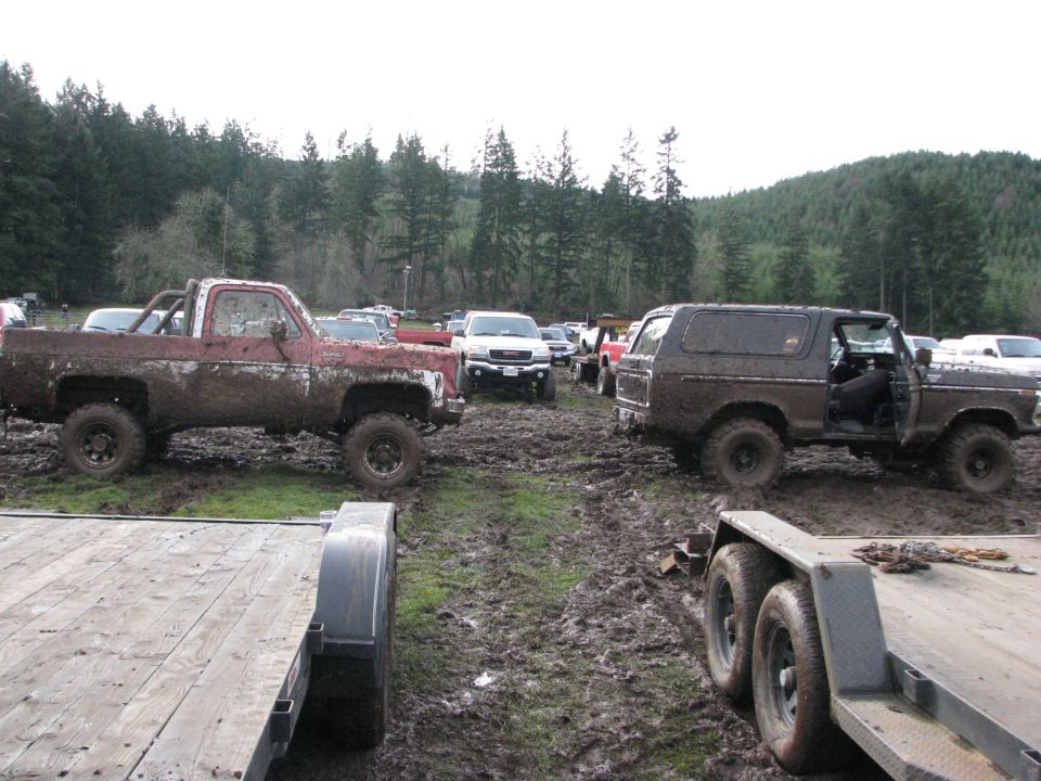 Muddy 1978 Ford Bronco with door open, parked in a muddy field