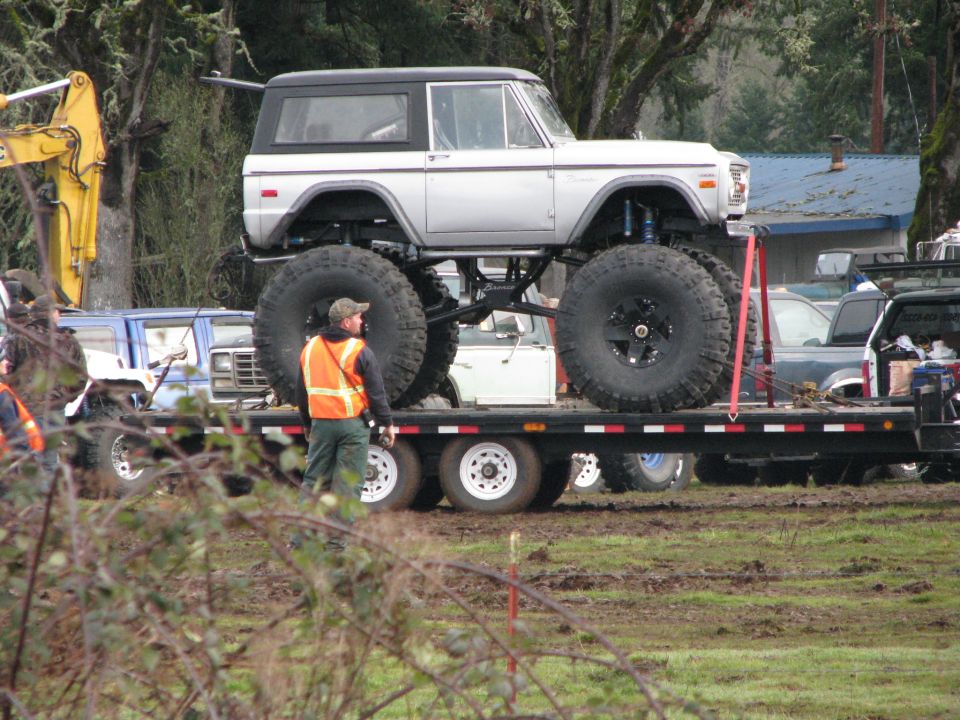 1978 Ford Bronco with massive tires on a flatbed trailer, being transported