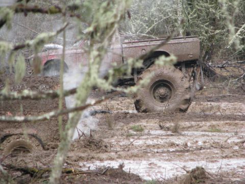 1978 Ford Bronco - A heavily soiled truck is stuck in thick mud and appears to be emitting steam.