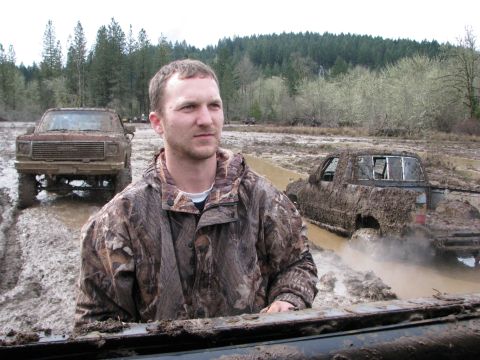 1978 Ford Bronco - Two trucks are stuck in the mud, with a man in a camouflage jacket in the foreground.