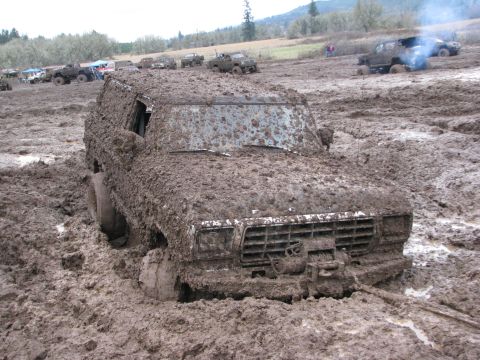 1978 Ford Bronco - Muddy 1978 Ford Bronco deep in a mud pit with other vehicles in the background.