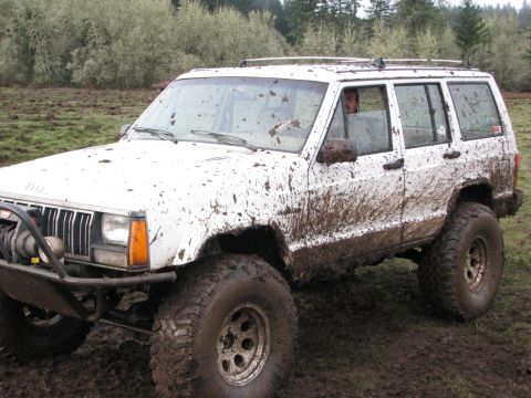 1978 Ford Bronco - Muddy Jeep Cherokee XJ navigates off-road terrain with large tires and winch.