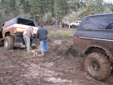 1978 Ford Bronco - Two SUVs are stuck in the mud, with people attempting to winch them out.
