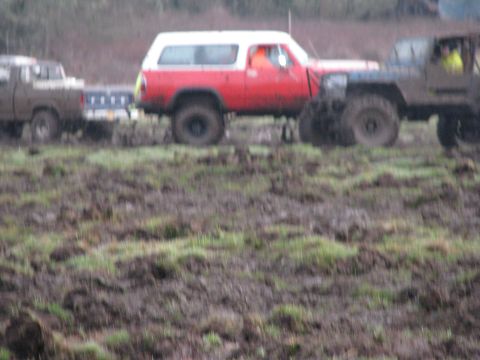 1978 Ford Bronco - Several off-road vehicles navigate a muddy terrain, with one red and white SUV prominently featured.