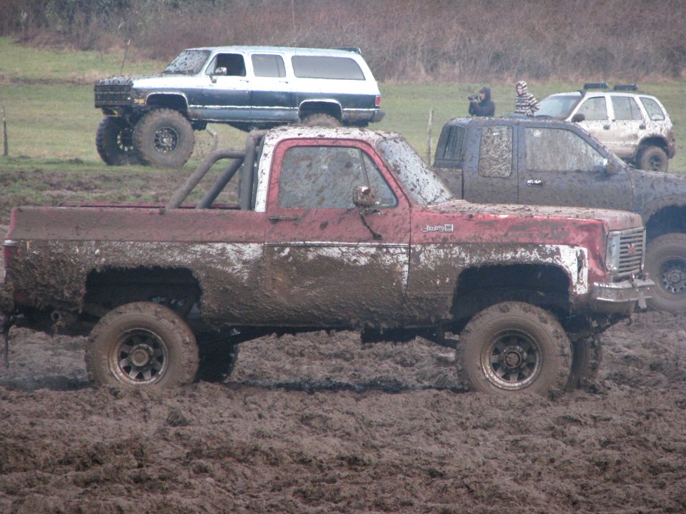 Red GMC pickup truck stuck in mud, side view
