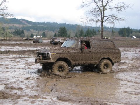 1978 Ford Bronco - A 1978 Ford Bronco navigates a challenging muddy terrain with other vehicles visible in the distance.