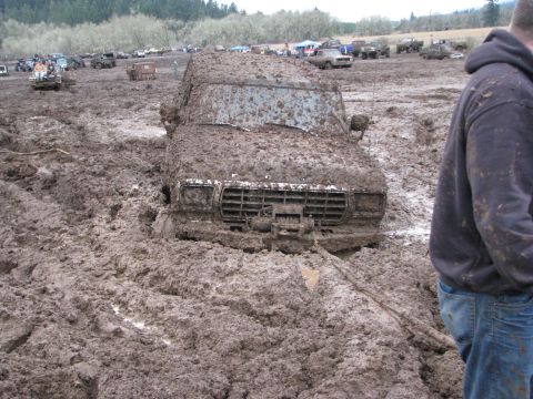 1978 Ford Bronco - A 1978 Ford Bronco is deeply stuck in mud, with other vehicles visible in the background at a mud bog event.