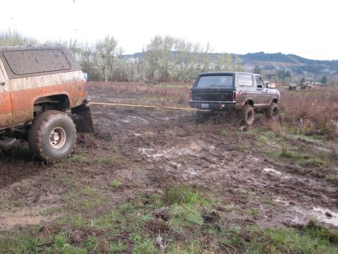 1978 Ford Bronco - Two off-road vehicles are stuck in the mud, with one towing the other through the mire.