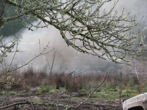 1978 Ford Bronco - A vehicle is partially obscured by smoke or steam while navigating a muddy, wooded area.
