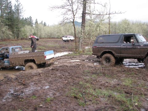 1978 Ford Bronco - Several off-road vehicles are stuck in deep mud during an outdoor event.