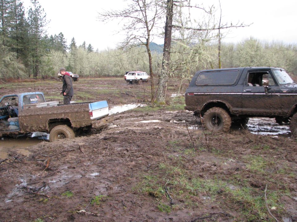 Mud-covered 1978 Ford Bronco in a muddy field, side view