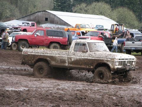 1978 Ford Bronco - Muddy 1977 Ford F-Series pickup truck navigates a muddy track with other vehicles present.