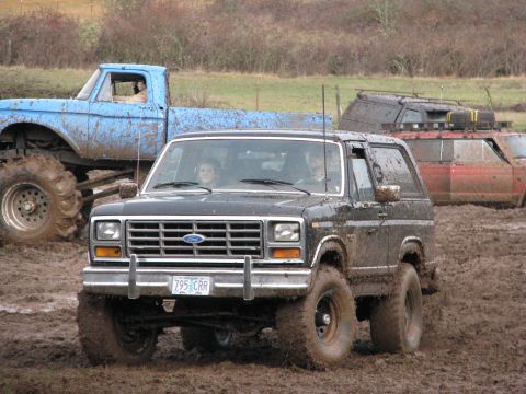 1978 Ford Bronco - This Ford Bronco is navigating a muddy terrain, with other vehicles visible in the background.