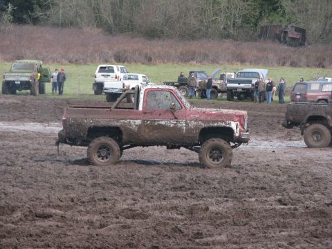 1978 Ford Bronco - Several off-road vehicles are seen in a muddy field during an event.