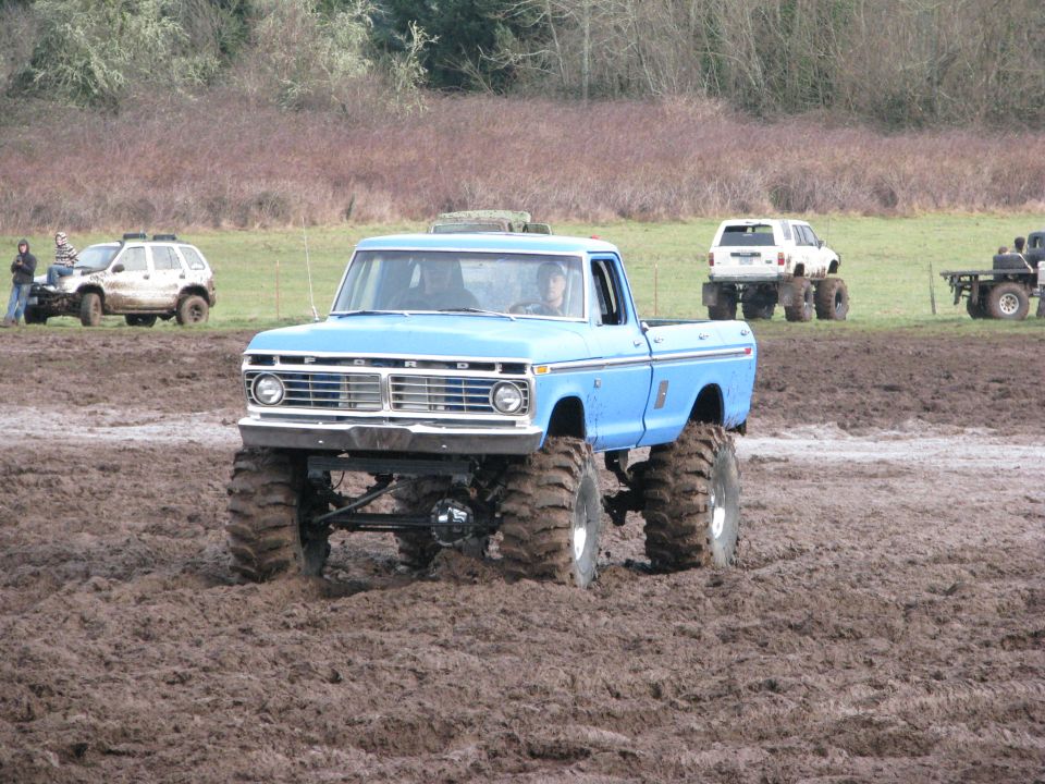 Blue pickup truck with large tires in mud; grille indicates 1973 model