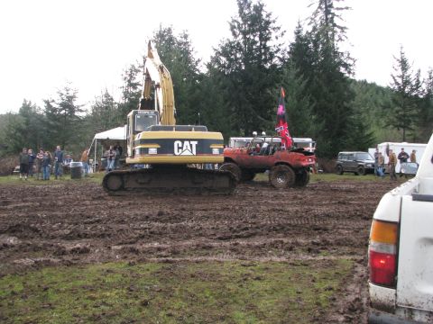 1978 Ford Bronco - An excavator and a modified off-road vehicle are stuck in the mud at an outdoor event.