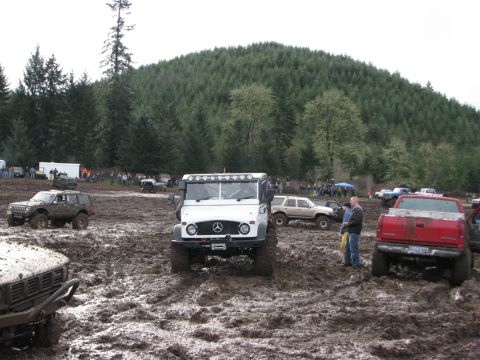 1978 Ford Bronco - Several off-road vehicles navigate a muddy course during an event.