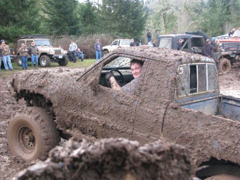 1978 Ford Bronco - Driver covered in mud while stuck in off-road event with other vehicles.