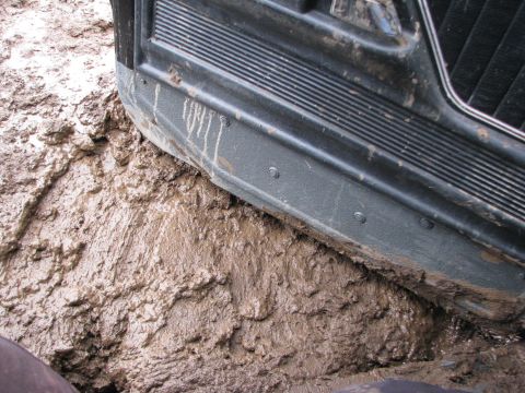 1978 Ford Bronco - The vehicle's lower body is caked in mud, indicating it is stuck in a muddy area.