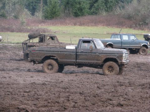 1978 Ford Bronco - A heavily mud-covered 1979 Ford F-Series pickup truck navigates a muddy terrain, with another truck visible in the background.