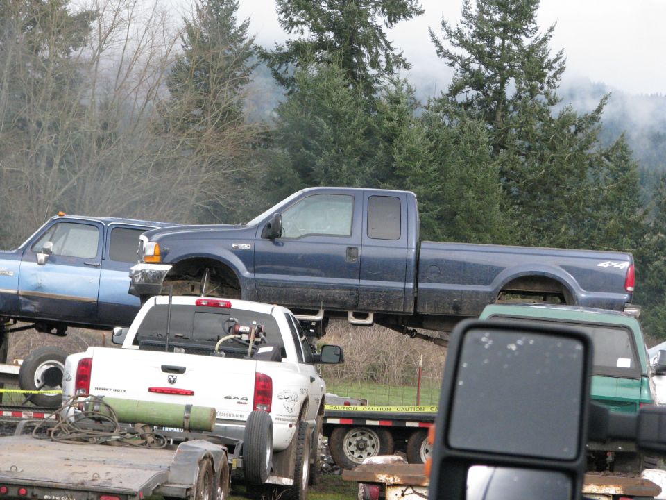 Blue Ford F-250 Super Duty pickup truck, missing front wheels, parked on trailers