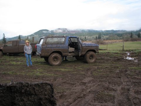 1978 Ford Bronco - A blue 1978 Ford Bronco is covered in mud, parked in a field with another vehicle and a person nearby.