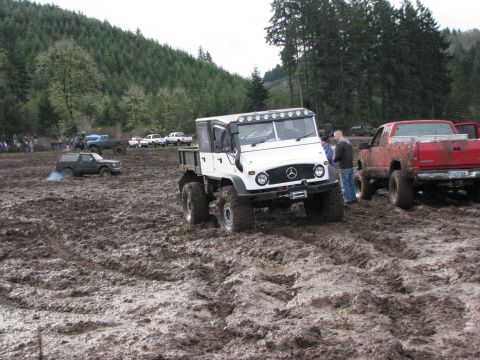 1978 Ford Bronco - Several off-road vehicles navigate a muddy terrain during an event.