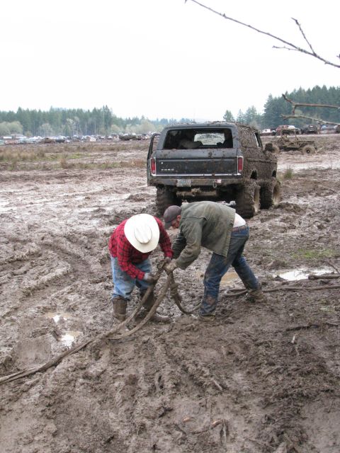 1978 Ford Bronco - Two men work to free a mud-covered 1978 Ford Bronco from a muddy field.