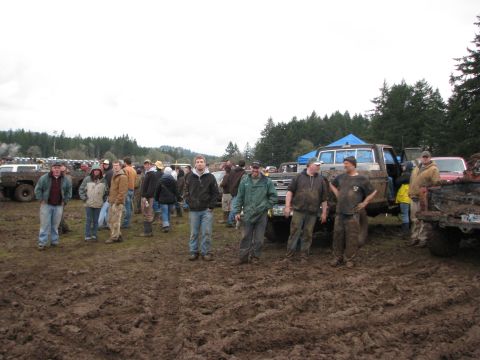1978 Ford Bronco - A muddy field filled with off-road vehicles and spectators under an overcast sky.