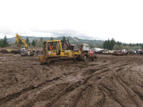 1978 Ford Bronco - Heavy machinery and vehicles navigate a muddy terrain, highlighting the challenging conditions of the off-road event.