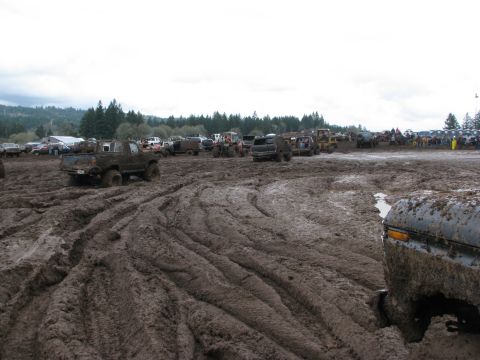 1978 Ford Bronco - Multiple off-road vehicles navigate a challenging mud course under an overcast sky.