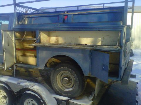 1994 Ford F-150 - The side of a blue utility truck bed is shown with multiple open storage compartments and a rack system above.