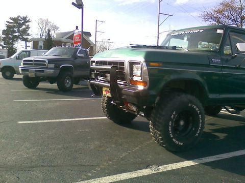 1979 Ford Bronco - Green Ford Bronco with off-road tires and a brush guard is parked in a lot.