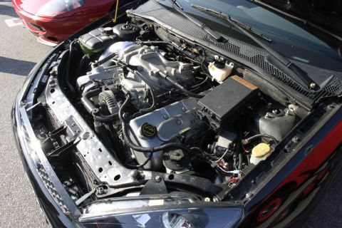 1993 Ford Taurus - Close-up of a car's engine bay, showing the V6 engine and other components. Another car is partially visible.
