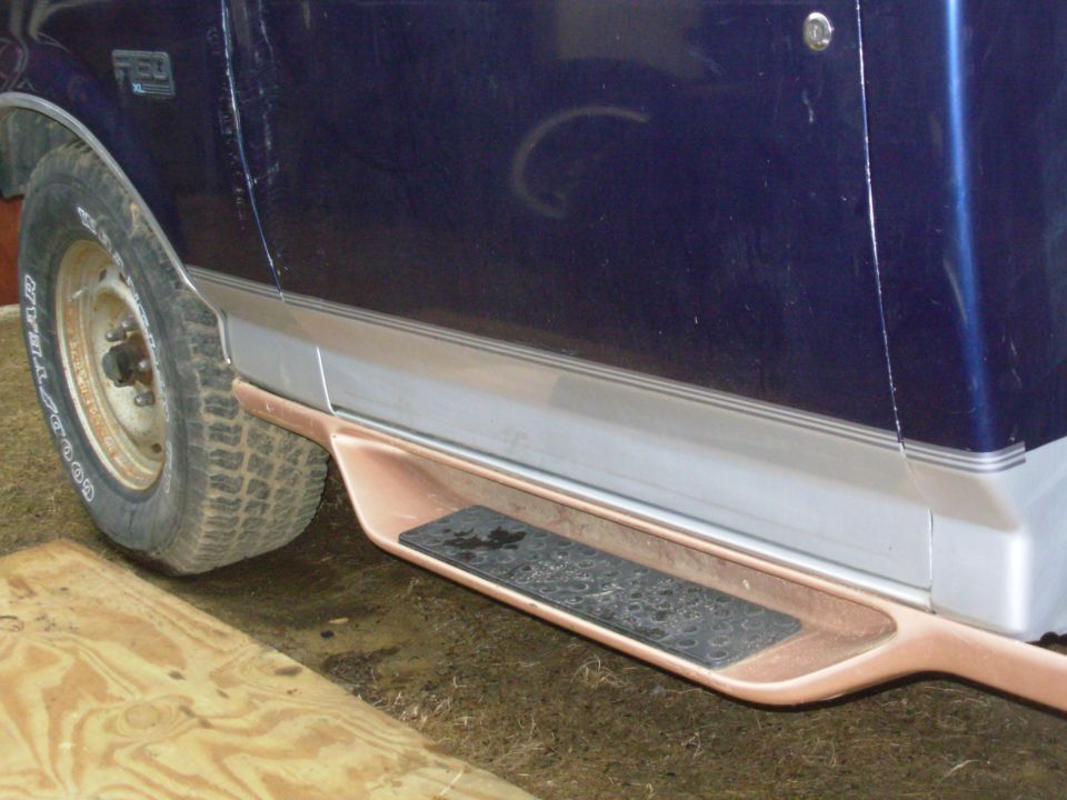 Lower body of a blue Ford F-150 with copper-colored running board step