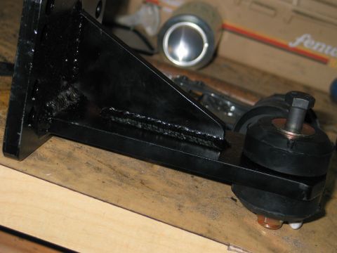 1984 Ford Bronco - Close-up of a black metal bracket with rubber isolators and hardware, likely a vehicle part.