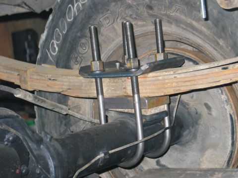 1984 Ford Bronco - Close-up view of a leaf spring and U-bolt suspension modification on a vehicle's rear axle.