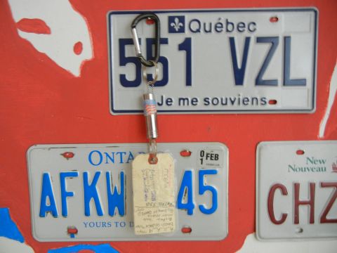 1999 Lincoln Town Car - Multiple license plates are displayed on a red wall, one with a keychain attached.